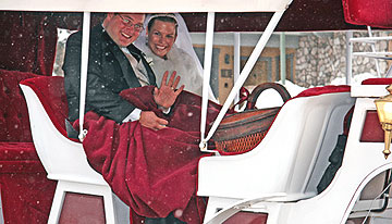 A newly married couple riding in a snow-covered, horse-drawn sled, covered with a Go-Blanket.